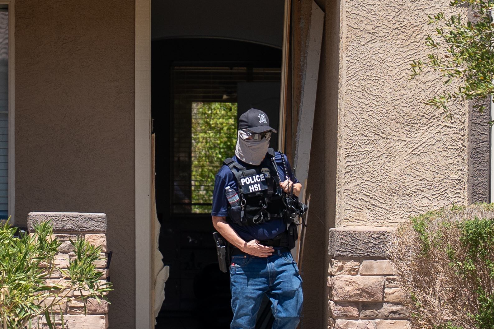 Federal agents in tactical gear storm the front entrance of a Glennwilde home during a Homeland Security operation on Chimayo Drive. Aug. 5, 2025. [David Iversen]