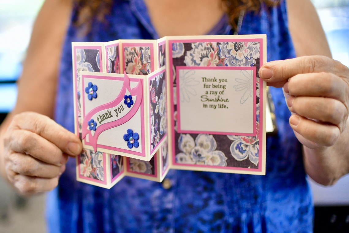 Carol Kasdorf, an Acacia Crossing resident, shows off a handcrafted greeting card she taught members of the Maricopa Golden Crafters group to make on July 28, 2025. [Monica D. Spencer]