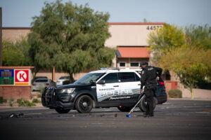 A Maricopa police officer sweeps debris from the road following a crash at John Wayne Parkway and Bowlin Road on April 9, 2026. [Monica D. Spencer]