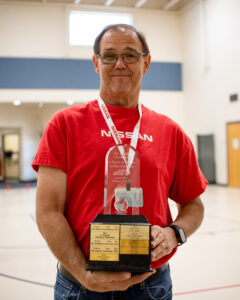 A volunteer from Nissan Technical Center stands with a 'World in Motion JetToy Challenge' trophy on May 12, 2026. The trophy is awarded to the winning class at Butterfield Elementary School classes every spring. [Monica D. Spencer]