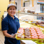 Sokvimom Koa, owner of Blooming Donuts, stands with a tray of donuts on June 6, 2026. [Monica D. Spencer]