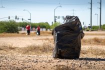 A full trash bag sits in the dirt during the Keep Maricopa Beautiful event at the Maricopa Community Center on May 30, 2026. [Ryan Tafoya]