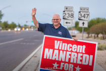 Vincent Manfredi waves while holding a campaign sign near SR 238 and SR 347 signs in Maricopa.